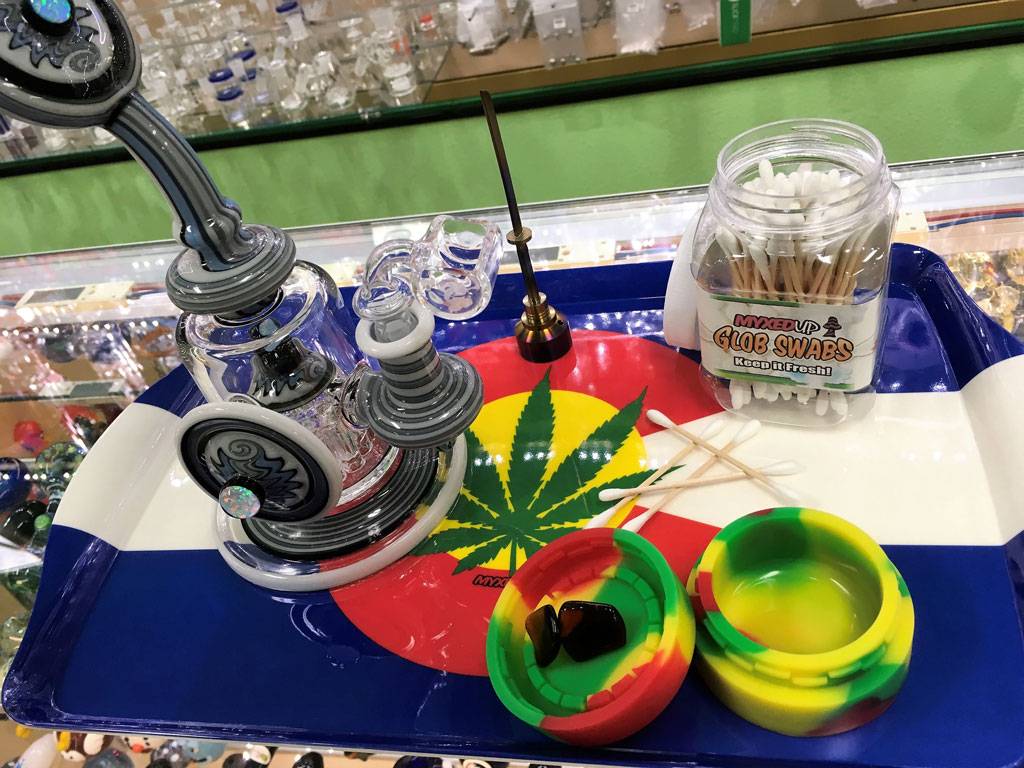 A Dab Rig sits in the ready position to enjoy cannabis concentrates sitting nearby in a silicone container.